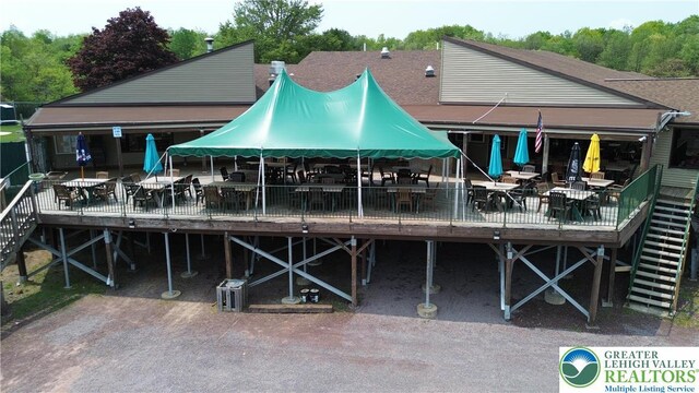 back of house featuring a deck, outdoor dining space, and roof with shingles