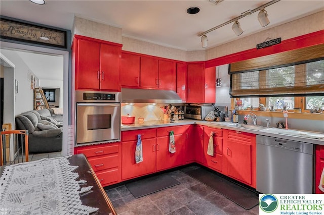 kitchen with appliances with stainless steel finishes, red cabinets, a sink, and under cabinet range hood