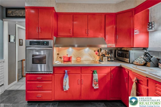 kitchen featuring stainless steel appliances, under cabinet range hood, red cabinets, light countertops, and ornamental molding
