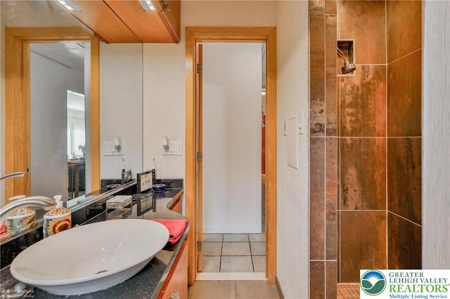 full bathroom featuring tile patterned flooring, vanity, and a tile shower