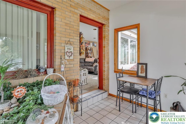 interior space with light tile patterned floors and brick wall