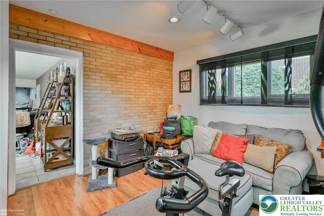 living area with brick wall, wood finished floors, and rail lighting