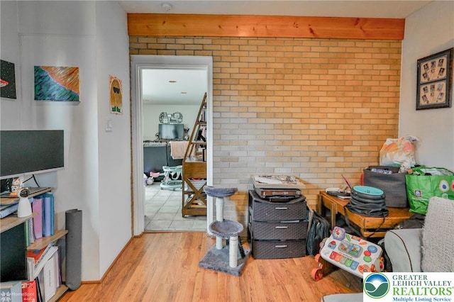 miscellaneous room with wood finished floors and brick wall