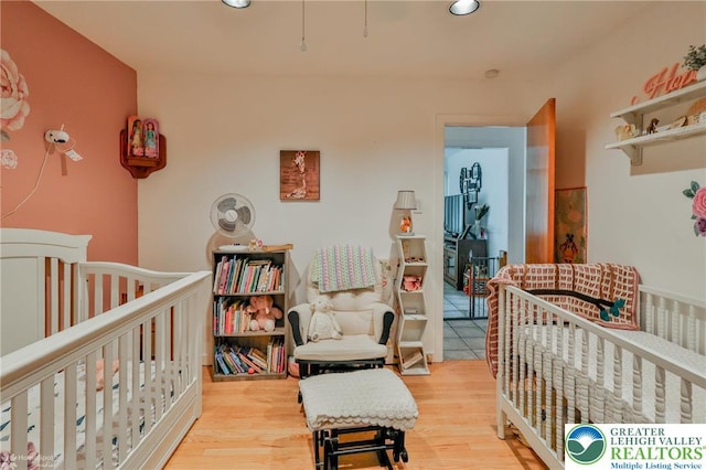 bedroom with recessed lighting, wood finished floors, and a nursery area