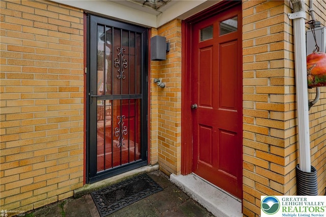 view of exterior entry featuring brick siding
