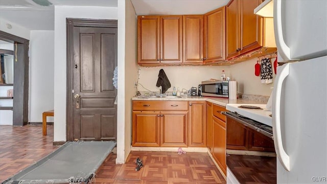 kitchen featuring white appliances, light countertops, light flooring, and brown cabinets