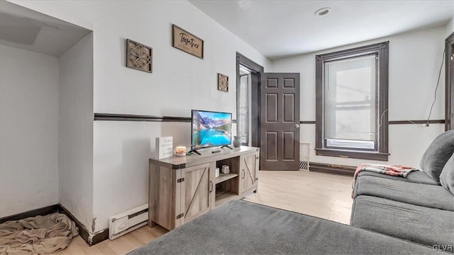 living room featuring a baseboard radiator, light wood-style flooring, and baseboards