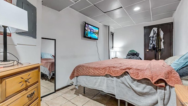 bedroom featuring a paneled ceiling, light tile patterned floors, and a closet