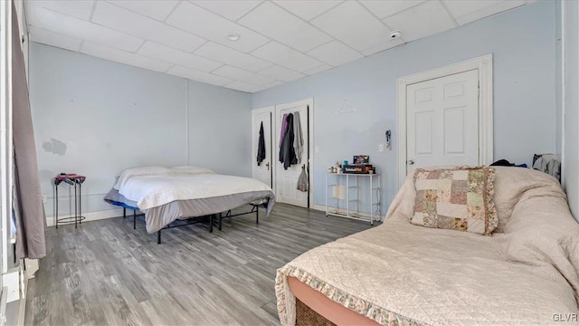 bedroom featuring light wood-style flooring, baseboards, a closet, and a drop ceiling