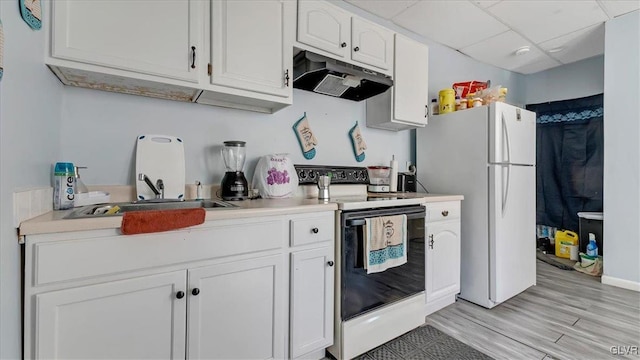 kitchen with range with electric cooktop, under cabinet range hood, freestanding refrigerator, white cabinets, and light countertops