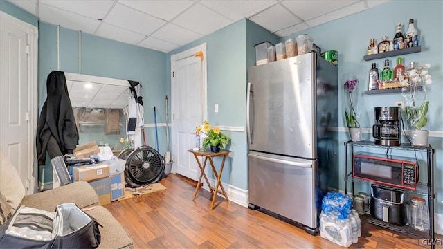 kitchen featuring freestanding refrigerator, a drop ceiling, and wood finished floors