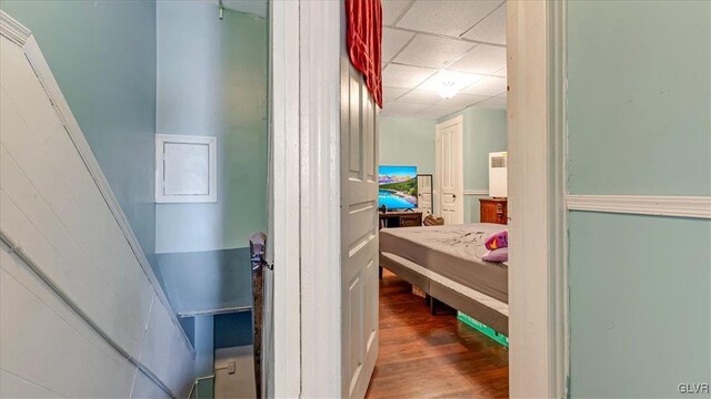 hallway with wood finished floors and a drop ceiling