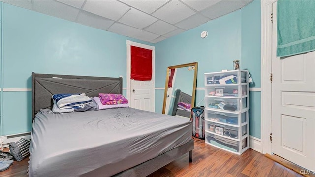 bedroom featuring wood finished floors and a drop ceiling