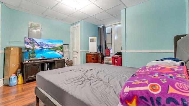 bedroom with wood finished floors and a paneled ceiling