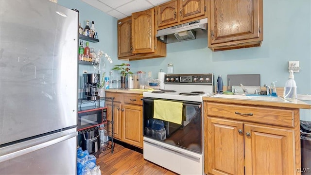 kitchen with freestanding refrigerator, white range with electric cooktop, under cabinet range hood, black microwave, and light countertops