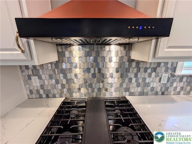130 Corktree Rd, Polk Twp, PA 18058 - detailed view of custom exhaust hood, decorative backsplash, gas stovetop, white cabinetry, and light stone counters