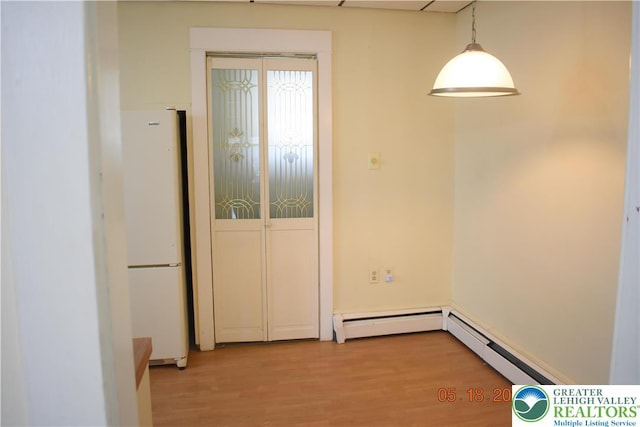 unfurnished dining area with a baseboard radiator and light wood-style flooring