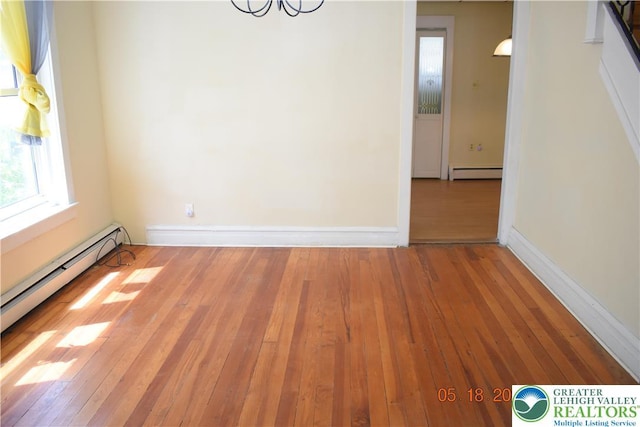 unfurnished dining area with a baseboard radiator, wood-type flooring, a chandelier, and baseboards
