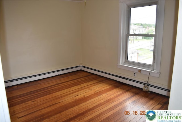 empty room featuring wood-type flooring and baseboard heating