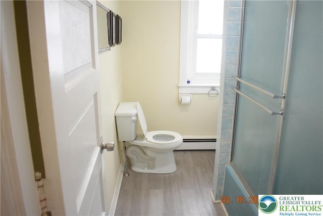 full bathroom featuring a baseboard radiator, toilet, wood finished floors, a shower with door, and baseboards