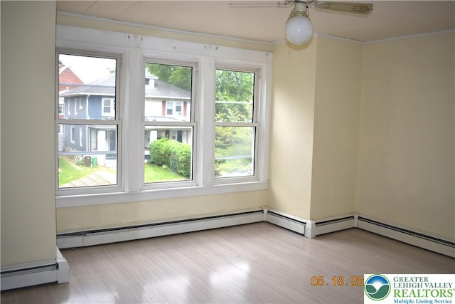 empty room featuring a baseboard heating unit, ornamental molding, a ceiling fan, and wood finished floors