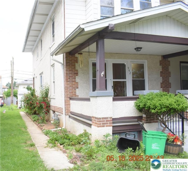 view of exterior entry featuring brick siding and covered porch