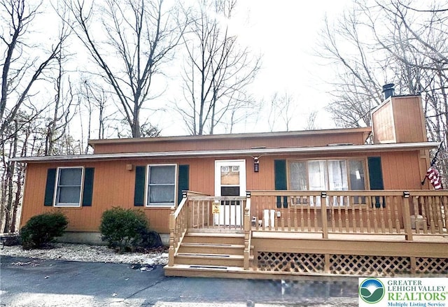 view of front of home featuring a chimney and a wooden deck