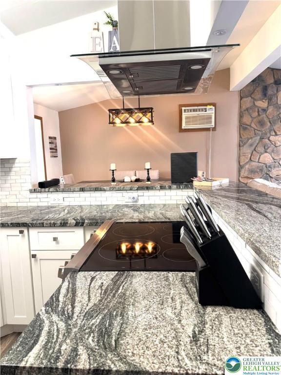 kitchen with white cabinetry, backsplash, dark stone countertops, a wall unit AC, and ventilation hood