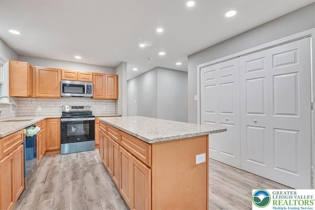 5653 Sullivan Trl, Plainfield Twp, PA 18064 - kitchen with appliances with stainless steel finishes, a sink, light wood-type flooring, a kitchen island, and decorative backsplash