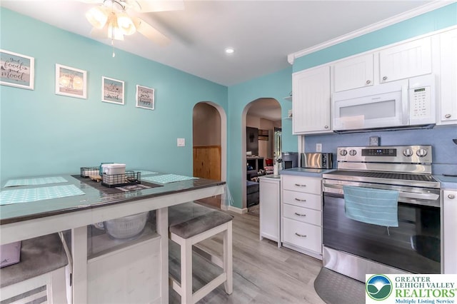 46 Jefferson St, Weatherly Borough, PA 18255 - kitchen with white microwave, stainless steel electric range, arched walkways, ceiling fan, and a kitchen breakfast bar
