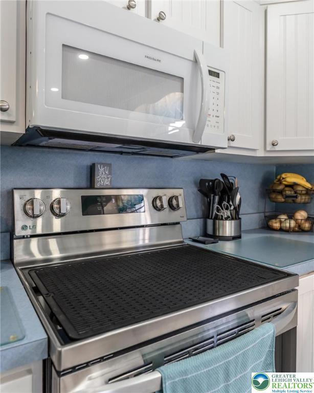 46 Jefferson St, Weatherly Borough, PA 18255 - detailed view of white microwave, stainless steel range with electric stovetop, and white cabinets