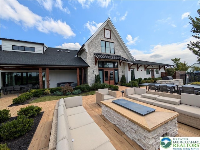6978 Pine Ln, East Allen Twp, PA 18014 - rear view of property with an outdoor living space with a fire pit, exterior kitchen, outdoor dining space, stone siding, and a shingled roof