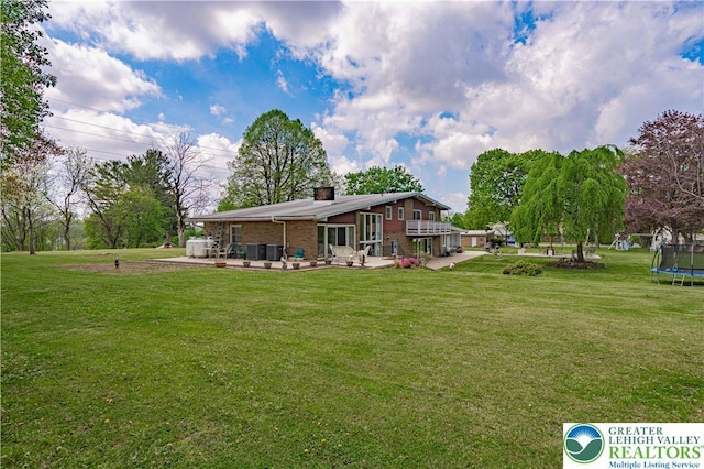 4205 Lehigh St, Whitehall Twp, PA 18052 - rear view of property featuring a trampoline, a chimney, a lawn, a patio, and brick siding