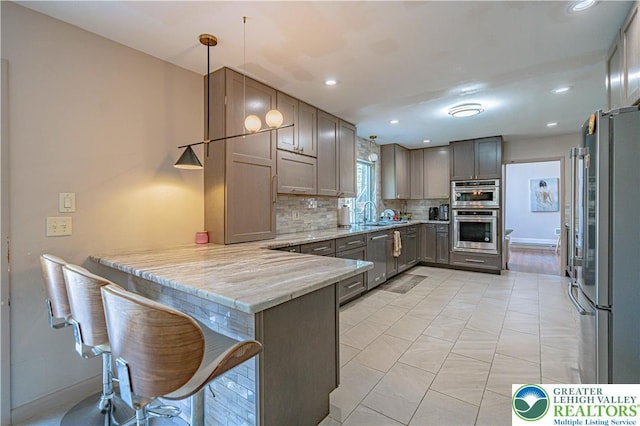 4205 Lehigh St, Whitehall Twp, PA 18052 - kitchen featuring stainless steel appliances, a peninsula, decorative backsplash, light stone counters, and decorative light fixtures