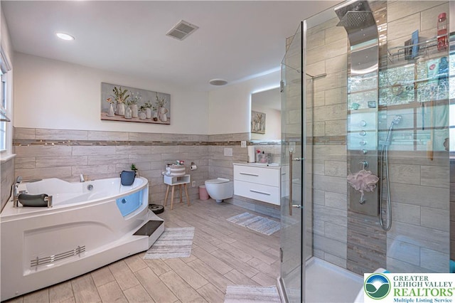 4205 Lehigh St, Whitehall Twp, PA 18052 - bathroom featuring tile walls, a stall shower, a bath, wainscoting, and wood finished floors