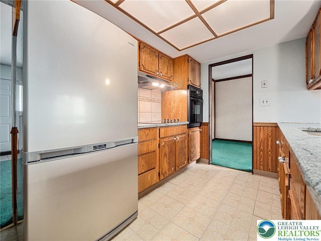 1218 Avocet Dr, Upper Macungie Twp, PA 18031 - kitchen featuring freestanding refrigerator, under cabinet range hood, oven, brown cabinetry, and backsplash