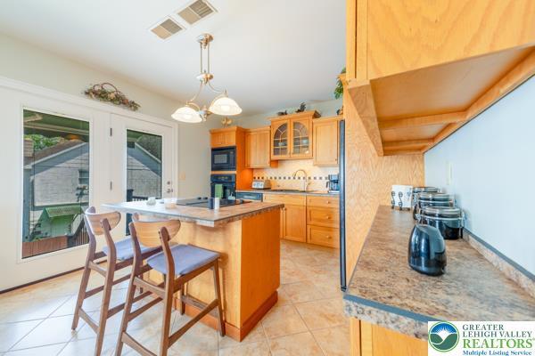 71 N 3rd St, Bangor Borough, PA 18013 - kitchen with black appliances, a kitchen breakfast bar, glass insert cabinets, a center island, and light tile patterned floors
