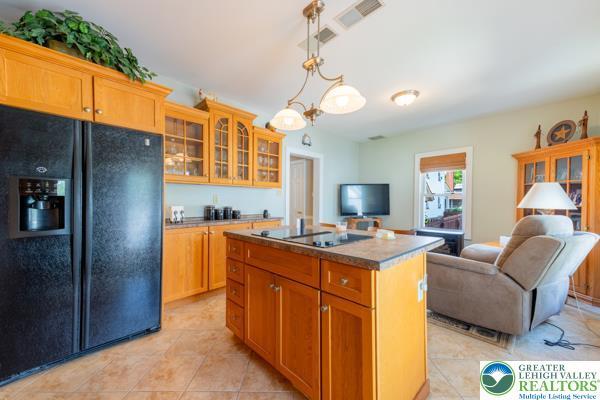 71 N 3rd St, Bangor Borough, PA 18013 - kitchen with black appliances, an island with sink, open floor plan, glass insert cabinets, and light tile patterned floors