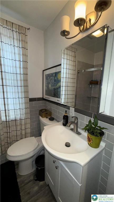 123 N Penn St, Allentown City, PA 18102 - bathroom with tile walls, a shower stall, vanity, toilet, and wood finished floors