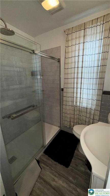 123 N Penn St, Allentown City, PA 18102 - bathroom featuring wood finished floors, tile walls, a shower stall, and toilet