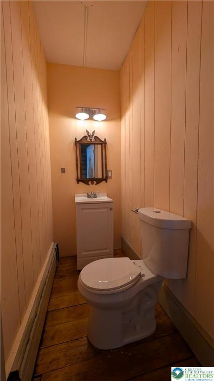30 S Broad St, East Bangor Borough, PA 18013 - bathroom featuring wood finished floors, a baseboard heating unit, toilet, vanity, and wood walls