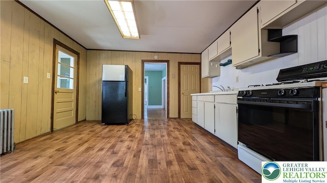 30 S Broad St, East Bangor Borough, PA 18013 - kitchen featuring freestanding refrigerator, range with gas cooktop, wood finished floors, white cabinetry, and wood walls