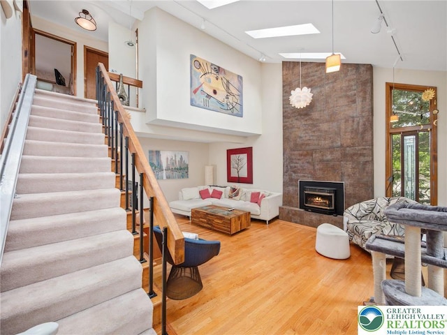4004 Westview Dr, South Whitehall Twp, PA 18104 - living room with rail lighting, wood finished floors, stairway, a fireplace, and a skylight