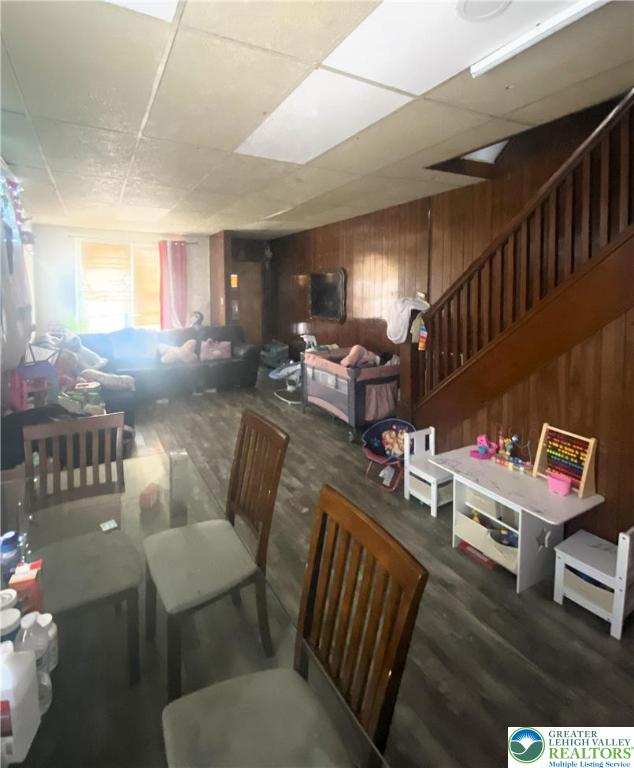 726 N 8th St, Allentown City, PA 18102 - dining space featuring wooden walls, stairs, wood finished floors, and a drop ceiling