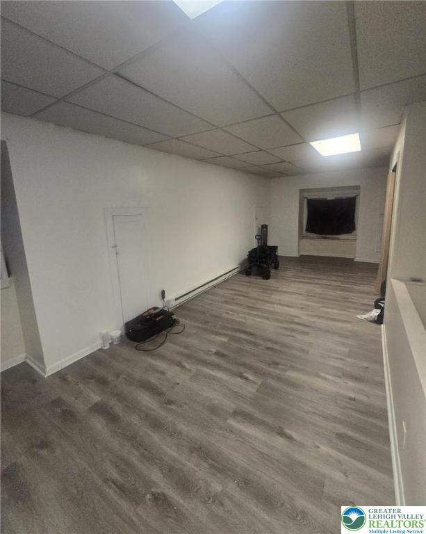 726 N 8th St, Allentown City, PA 18102 - finished below grade area featuring a baseboard heating unit, a paneled ceiling, wood finished floors, and baseboards