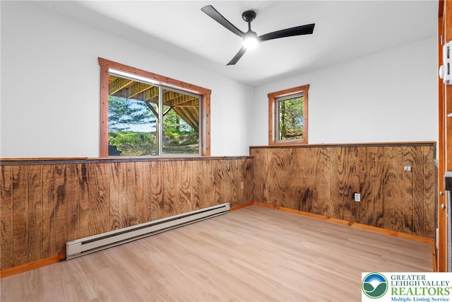 2107 Lenape Ter, Barrett Twp, PA 18325 - empty room featuring a baseboard heating unit, wood finished floors, wainscoting, ceiling fan, and wooden walls