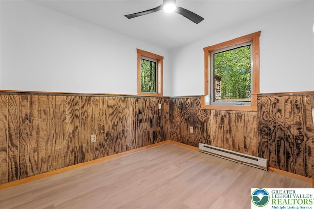 2107 Lenape Ter, Barrett Twp, PA 18325 - unfurnished room featuring a baseboard radiator, wainscoting, wood finished floors, plenty of natural light, and ceiling fan