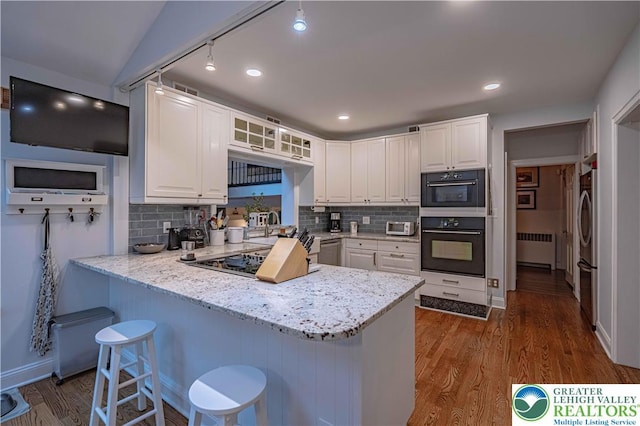 306 W Paxinosa Rd, Forks Twp, PA 18040 - kitchen with radiator, gas cooktop, a peninsula, white cabinetry, and a breakfast bar area