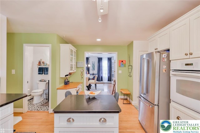 113 S Fairview St, Macungie Borough, PA 18062 - kitchen with freestanding refrigerator, oven, white cabinets, dark countertops, and light wood-style floors