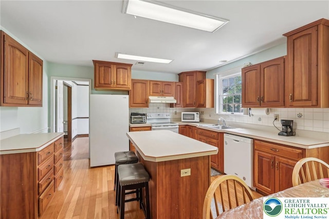 1450 Springhouse Rd, South Whitehall Twp, PA 18104 - kitchen with white appliances, under cabinet range hood, a sink, a kitchen bar, and decorative backsplash